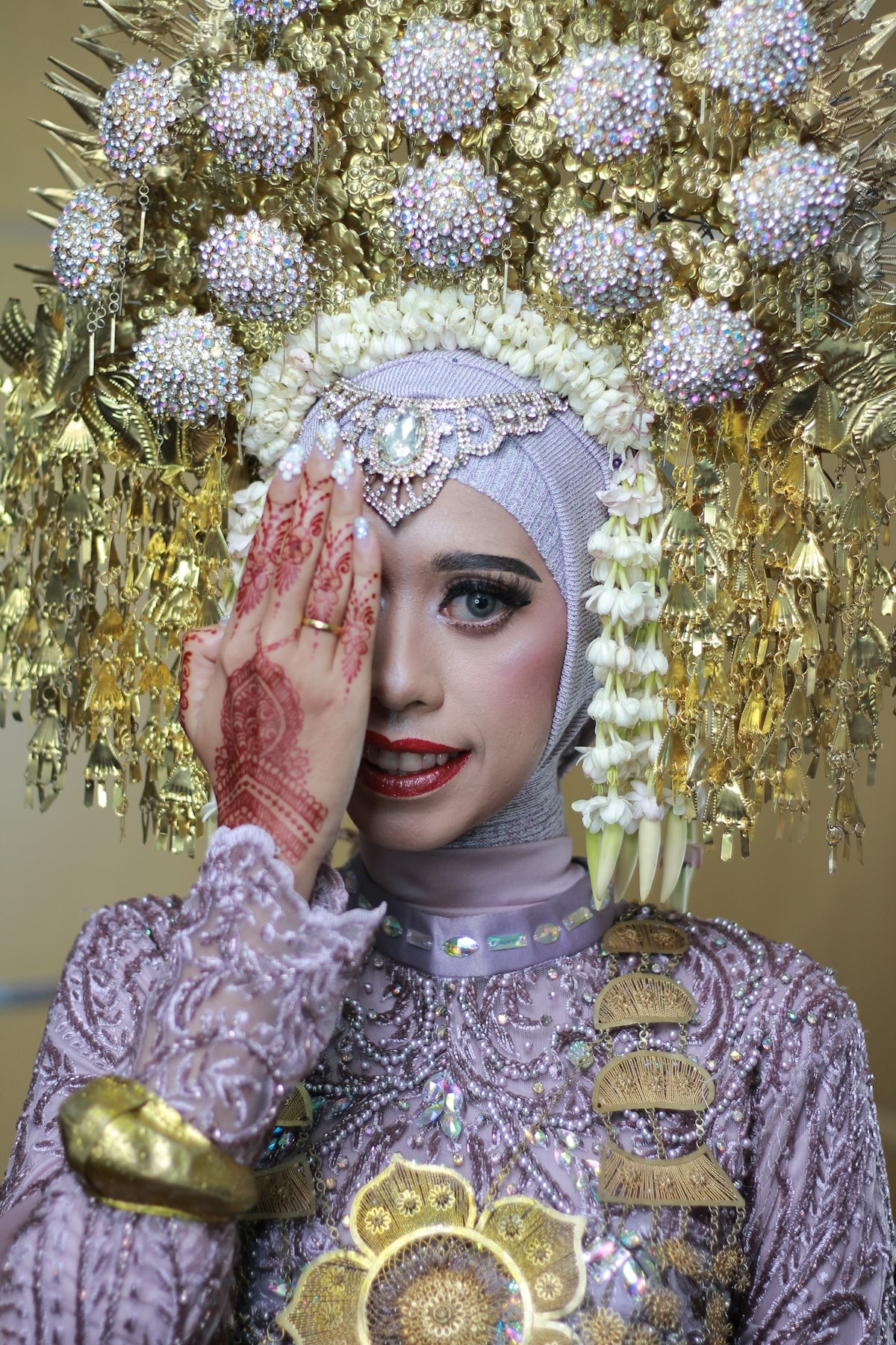a woman wearing a headdress and holding her hands to her face