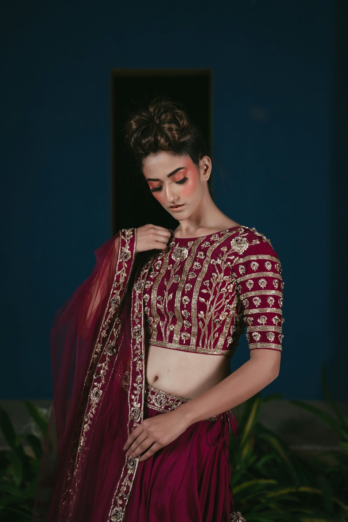 Woman in ornate maroon lehenga with elaborate makeup