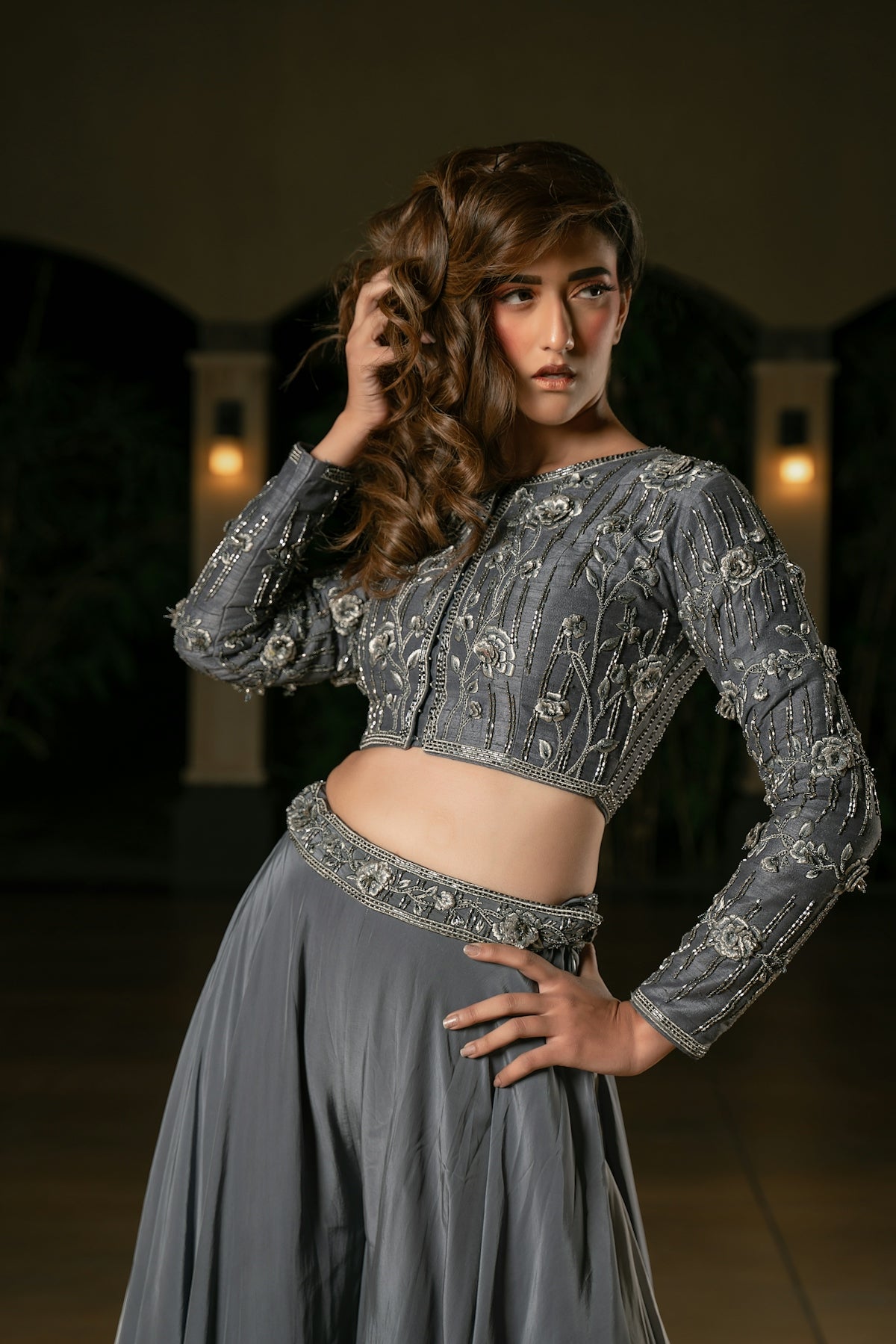 A woman in a grey embellished lehenga poses elegantly.