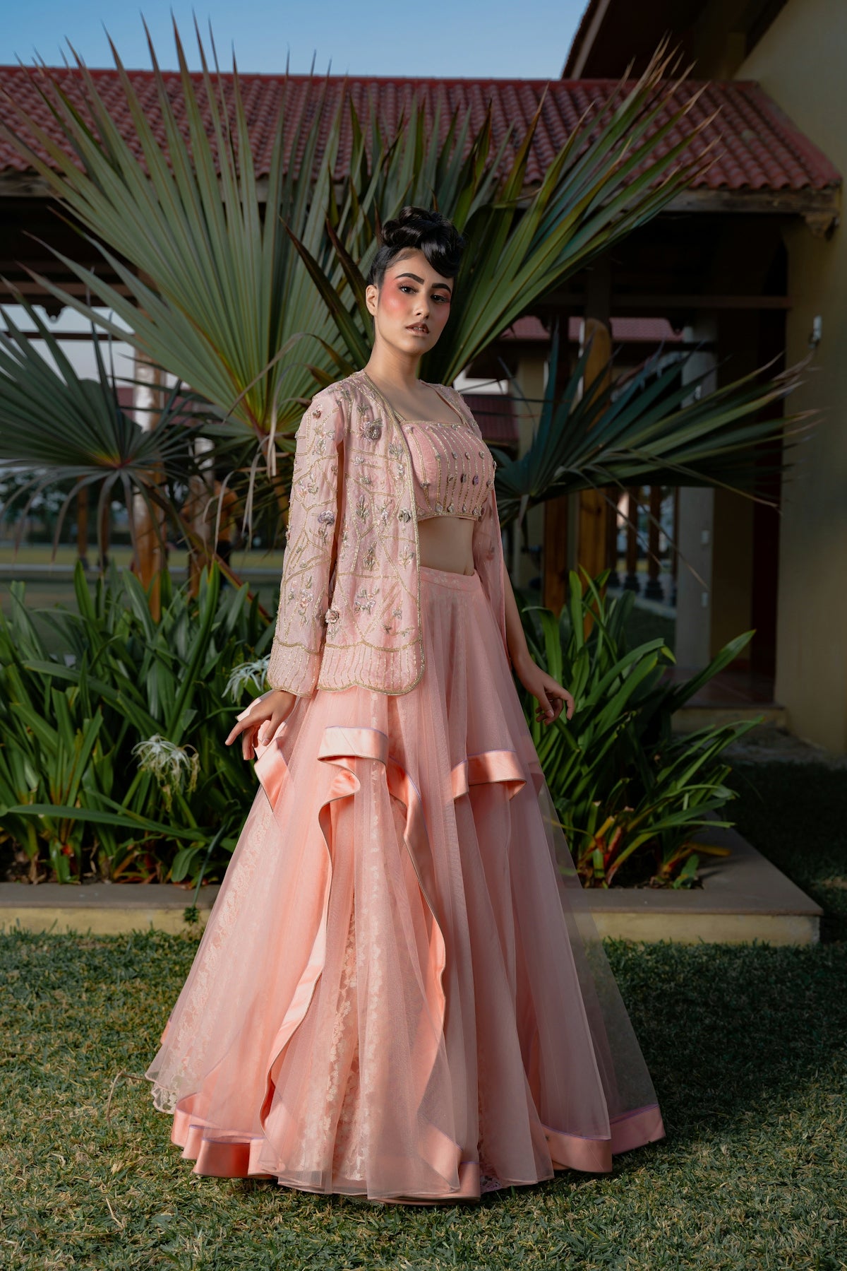 Woman in elegant peach lehenga with floral jacket.