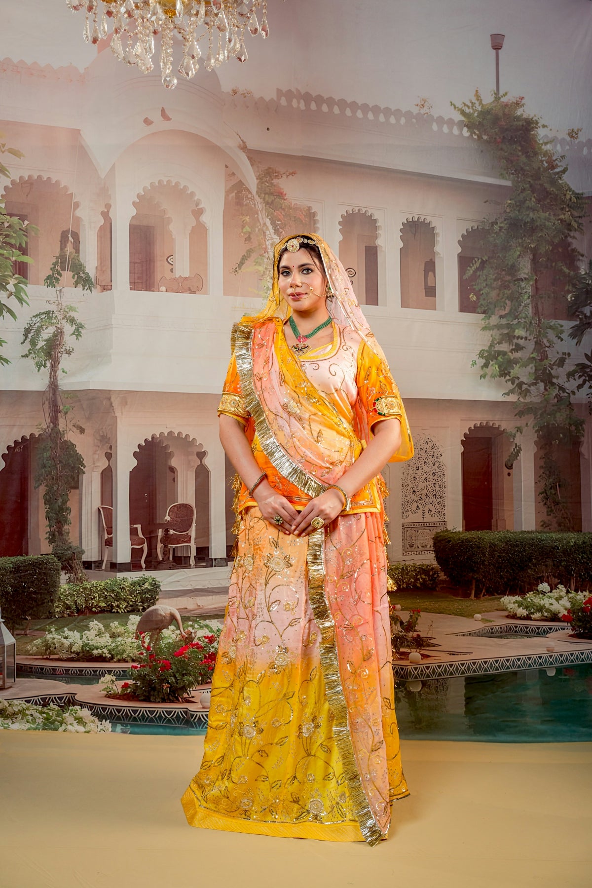 Woman in traditional indian attire stands before a palace backdrop.