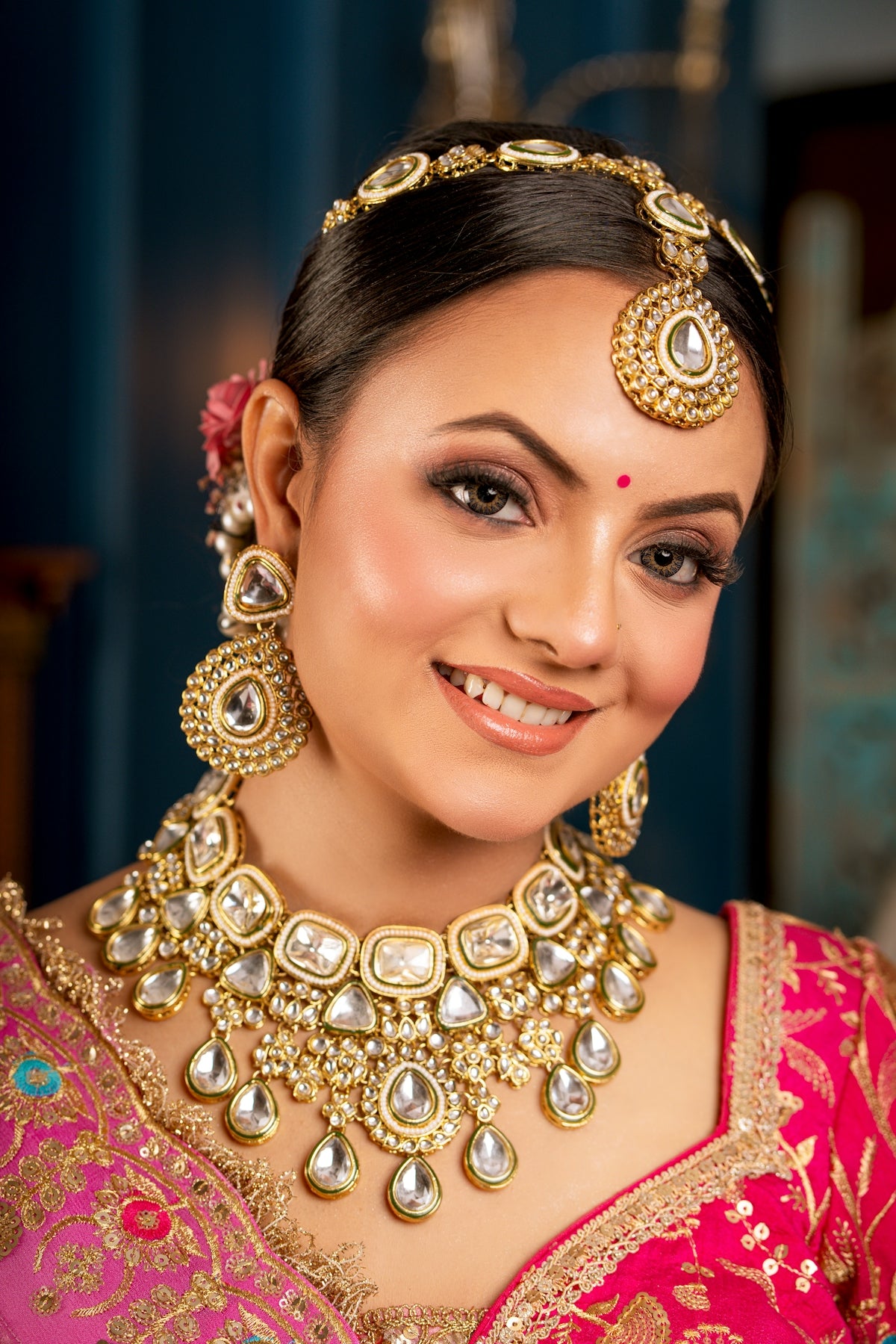 A smiling woman adorned in traditional indian jewelry and attire.