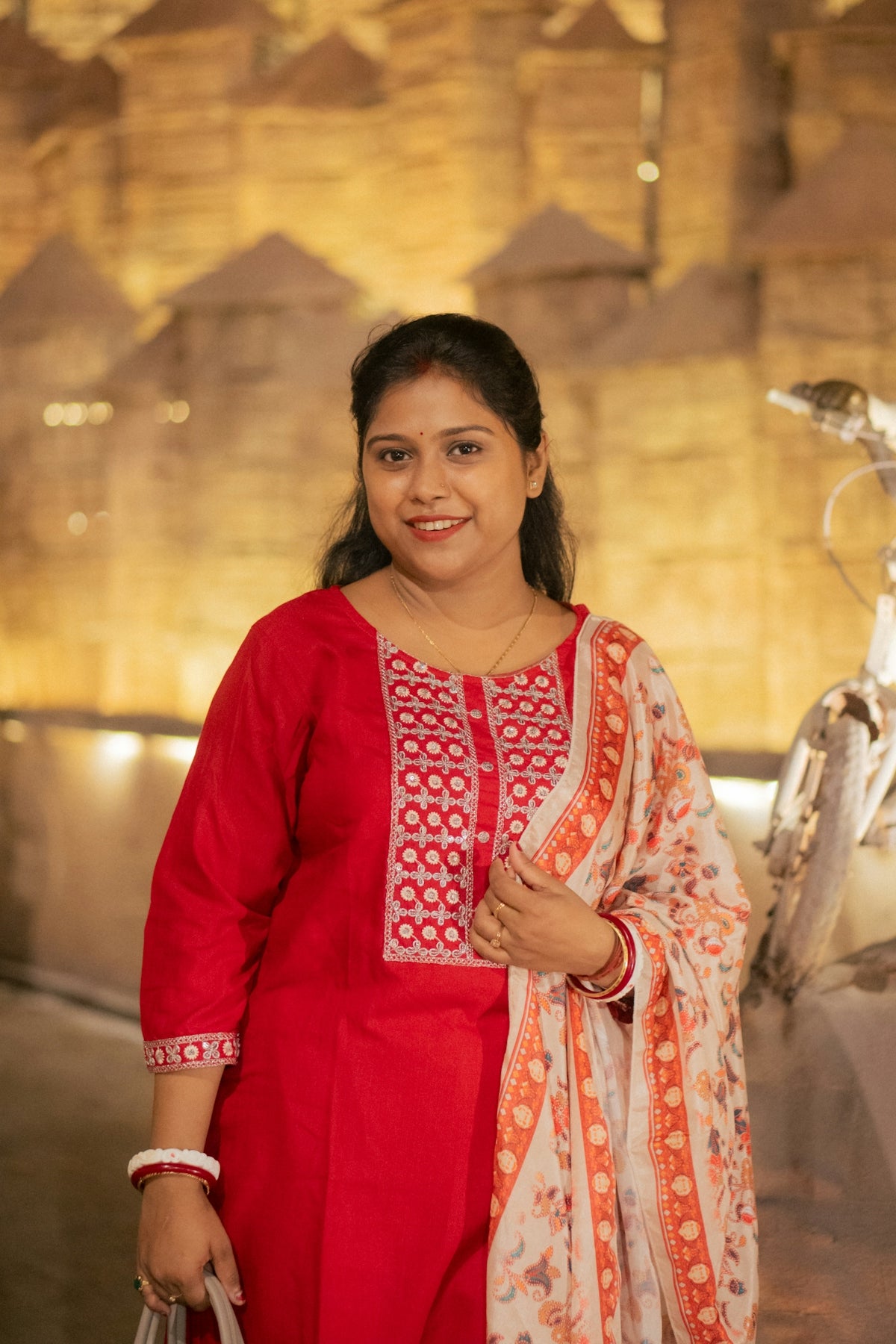 A woman in a red kurta with a floral scarf.