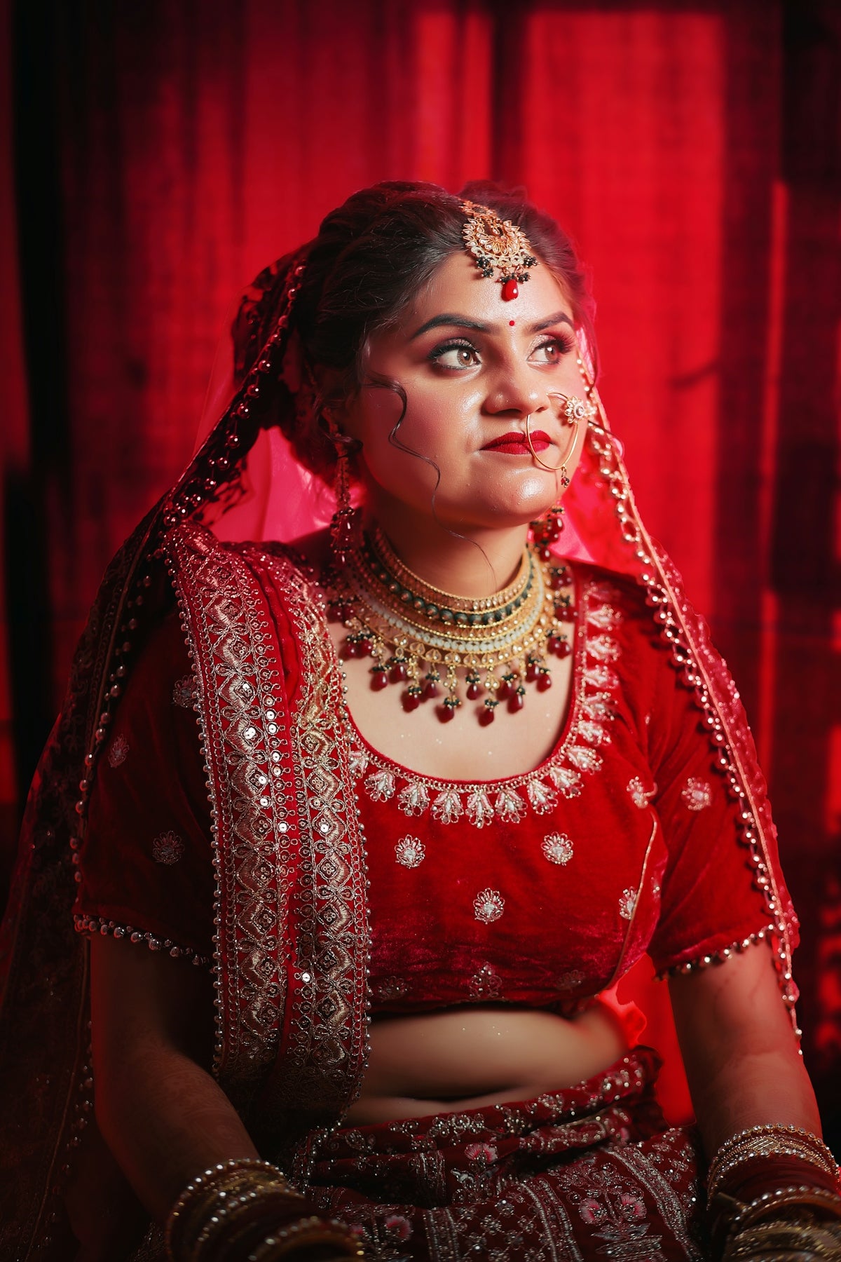 Bride in red traditional indian wedding attire with jewelry.