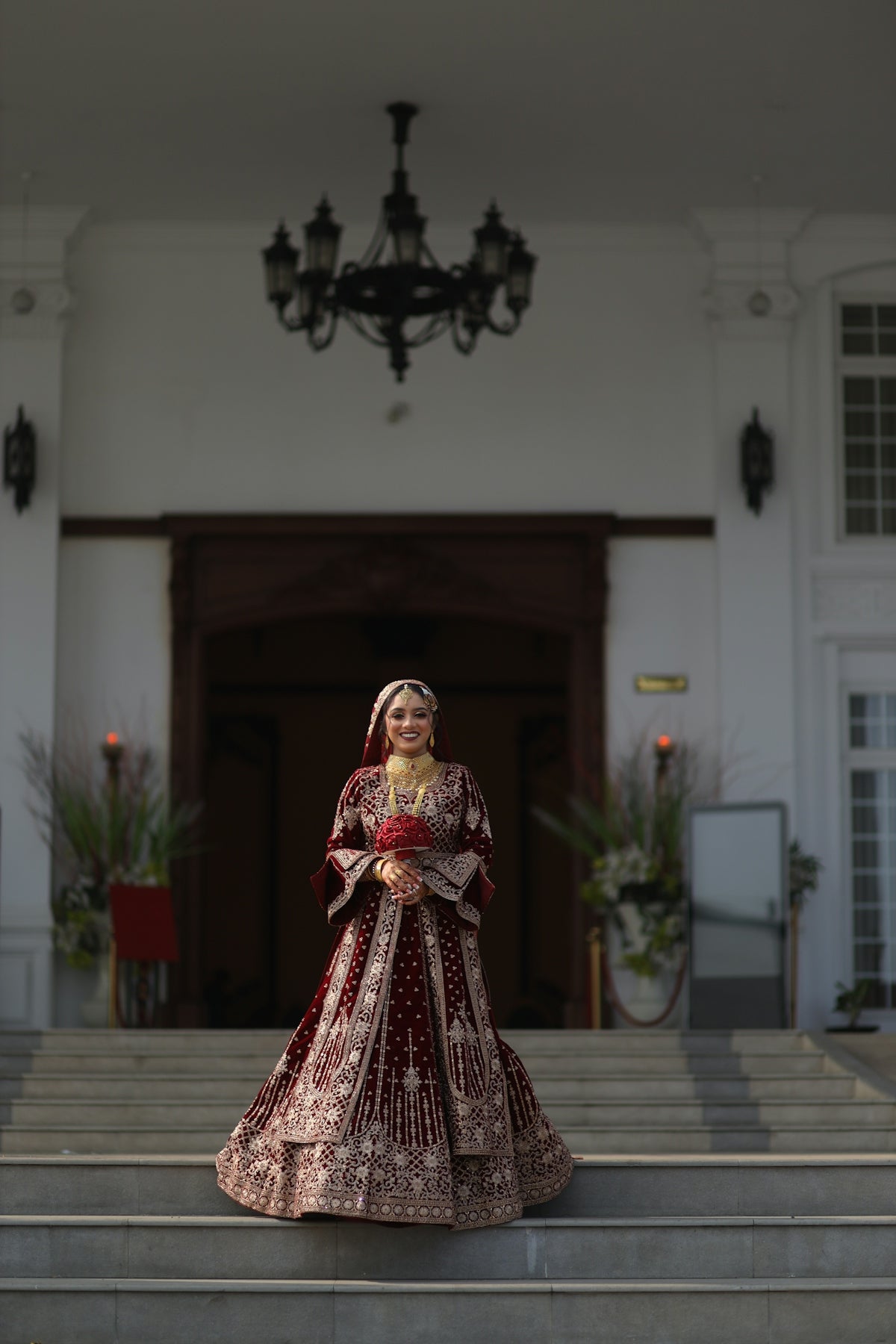 Bride in ornate red lehenga standing on steps