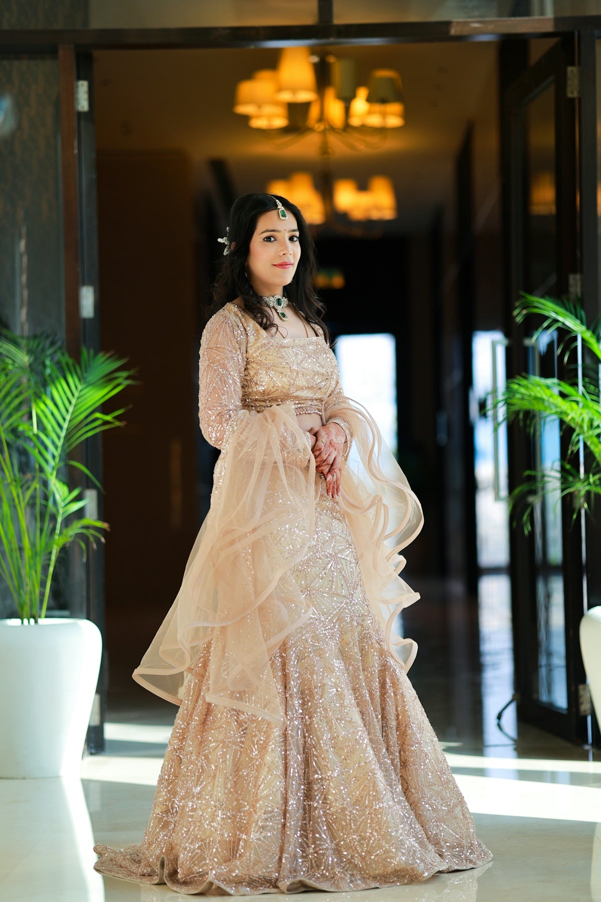 A woman in a sparkling gold lehenga poses elegantly.