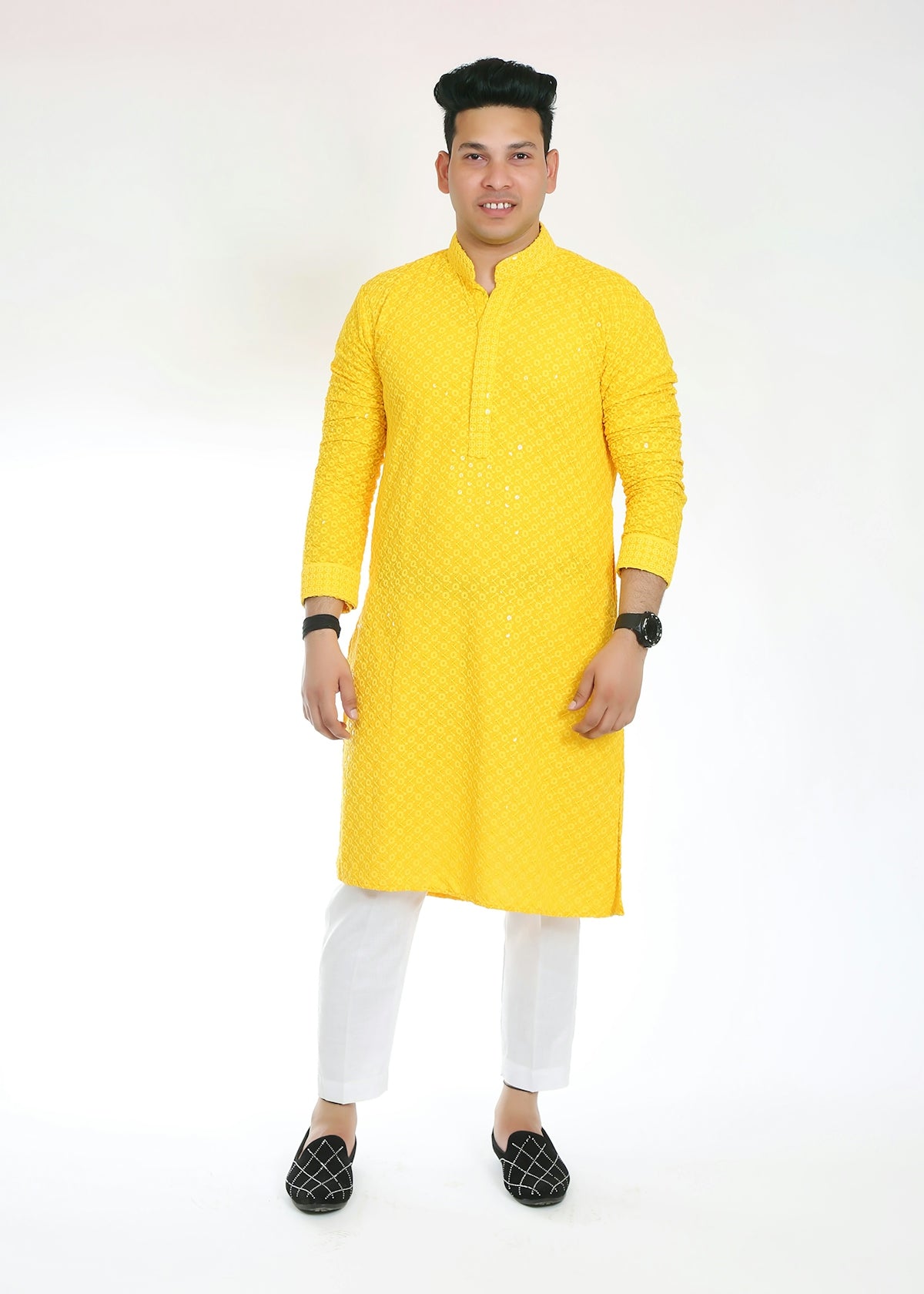 Man in yellow kurta and white pants smiles