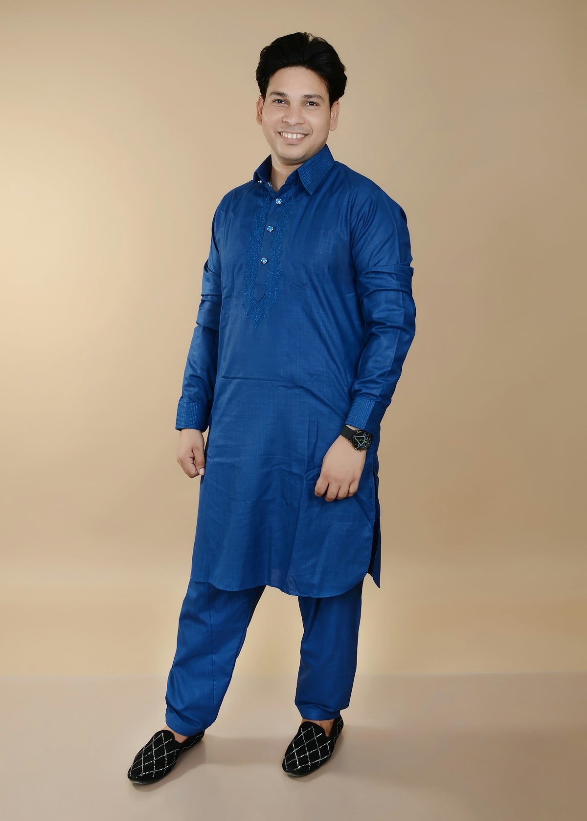 A man in a blue kurta and pants smiles