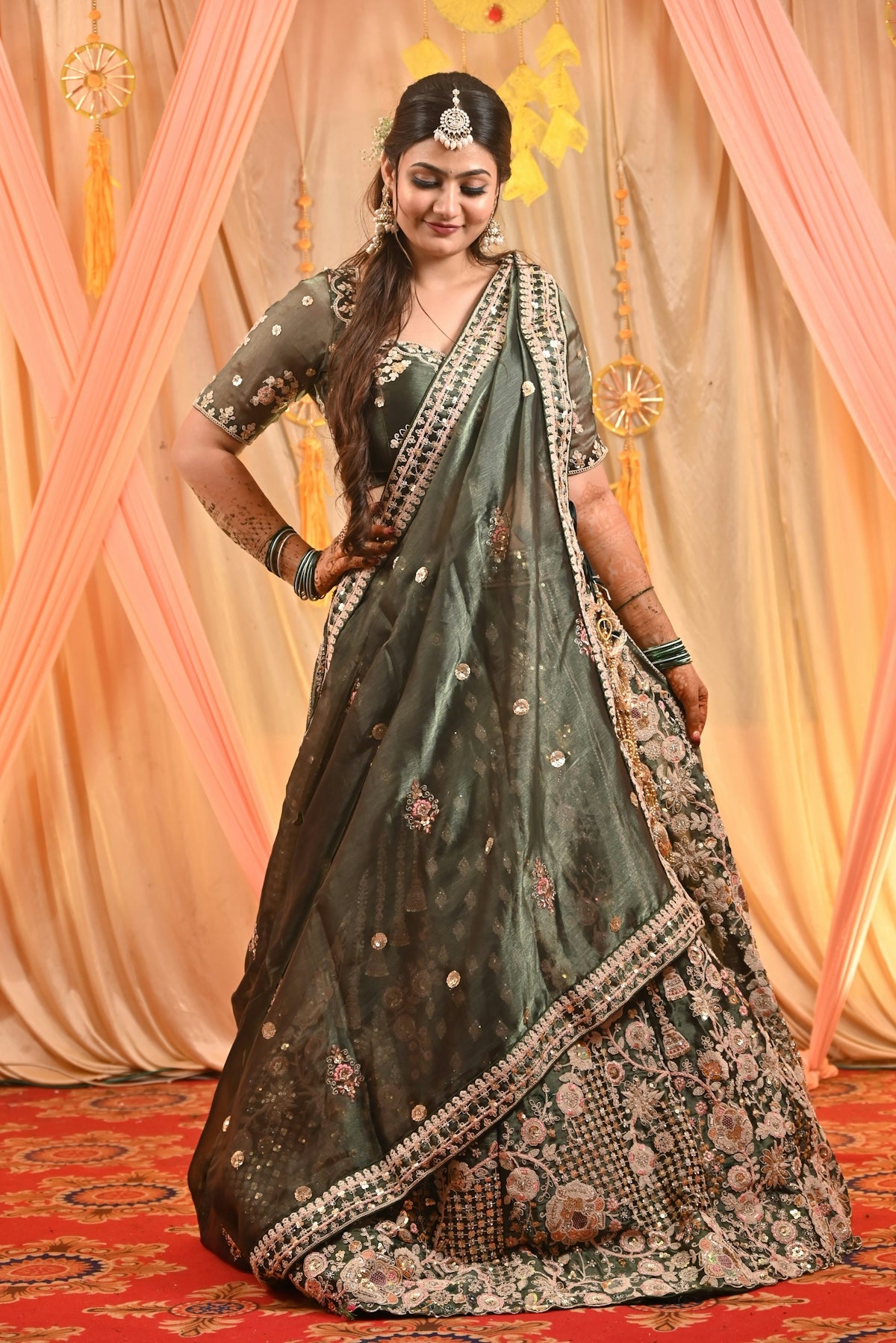 A woman in a green lehenga with intricate embroidery.