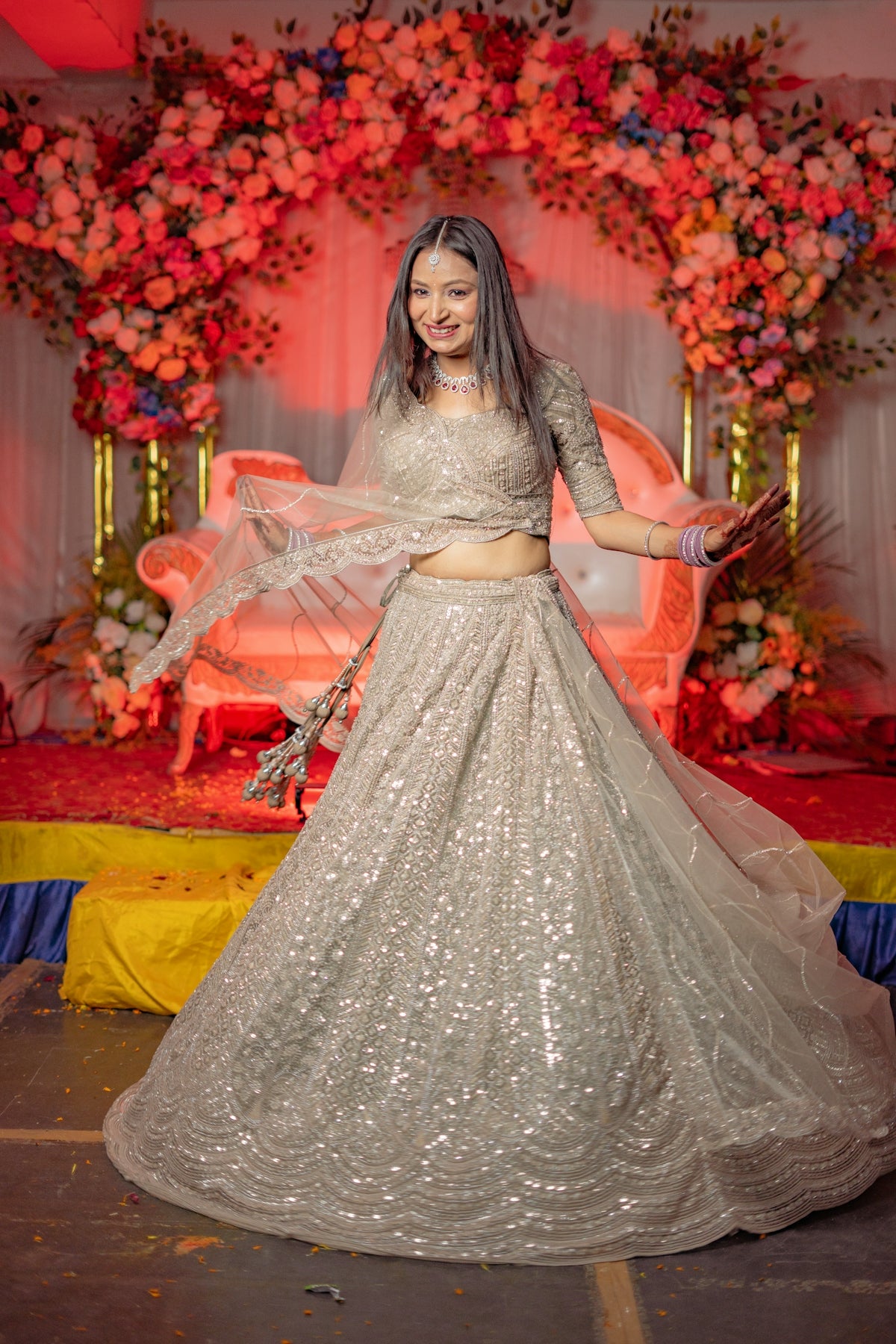A woman in a sparkly lehenga dances at a celebration.