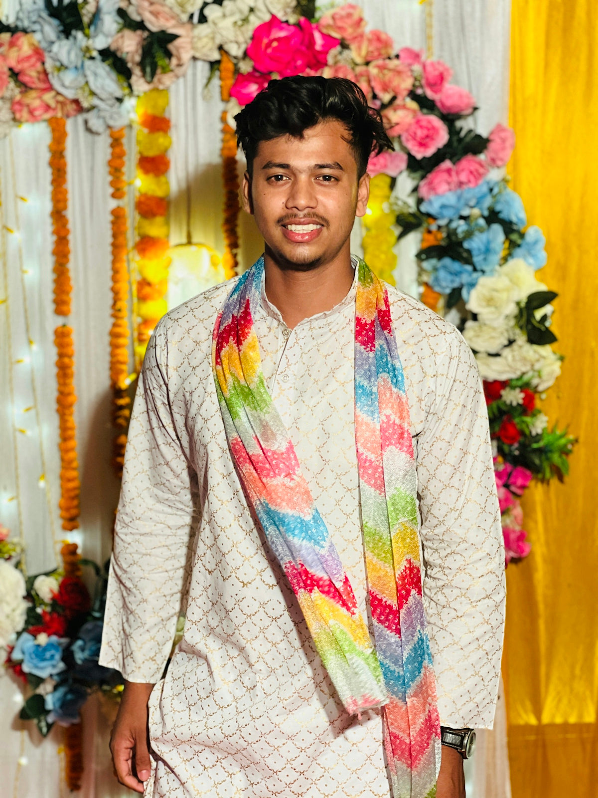 Smiling young man in traditional kurta and colorful scarf.