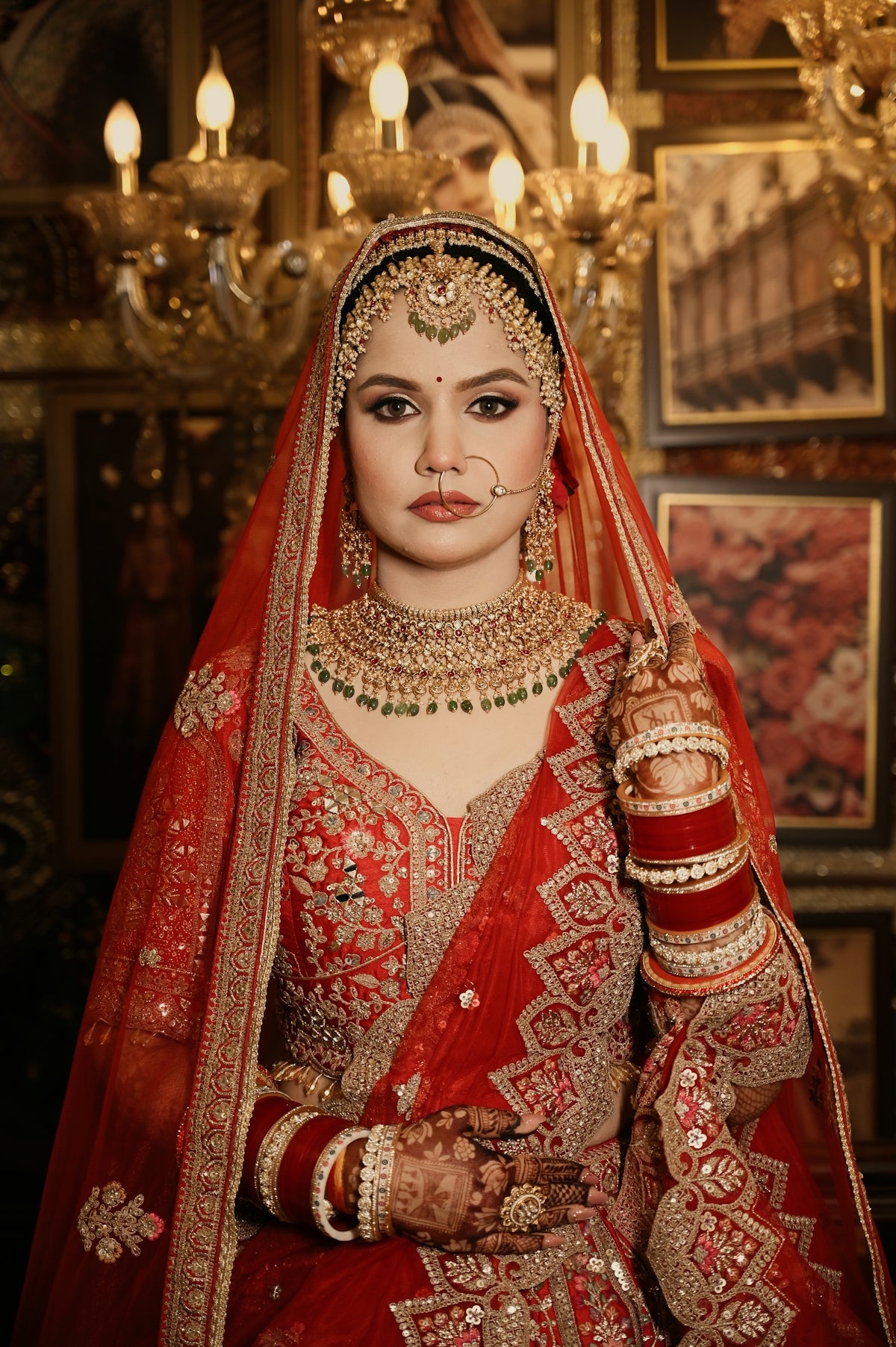 A woman in a red bridal lehenga with gold embroidery and traditional jewelry